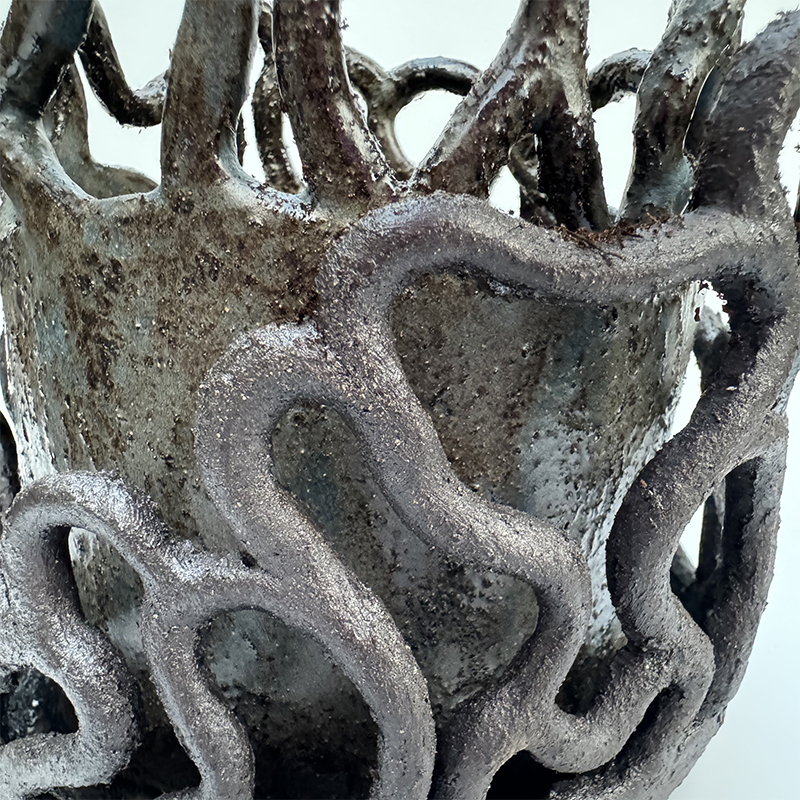 Coiled sculptural elements of a fully fired and glazed planter - some left raw unglazed textural black, some glazes in a blue satin glaze