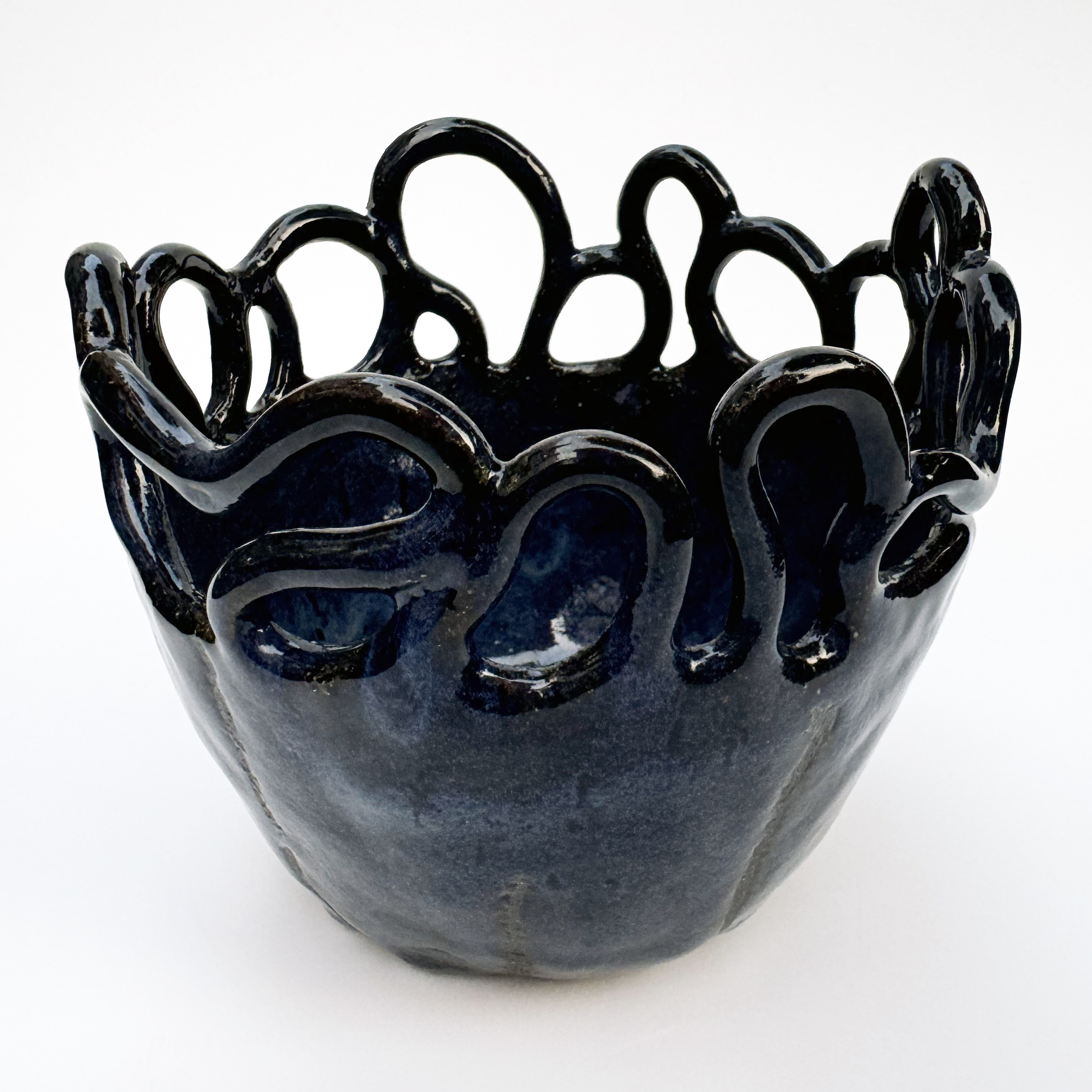 The bowl's form has coral-like coils coming out of the rim that curl back down to the rim.