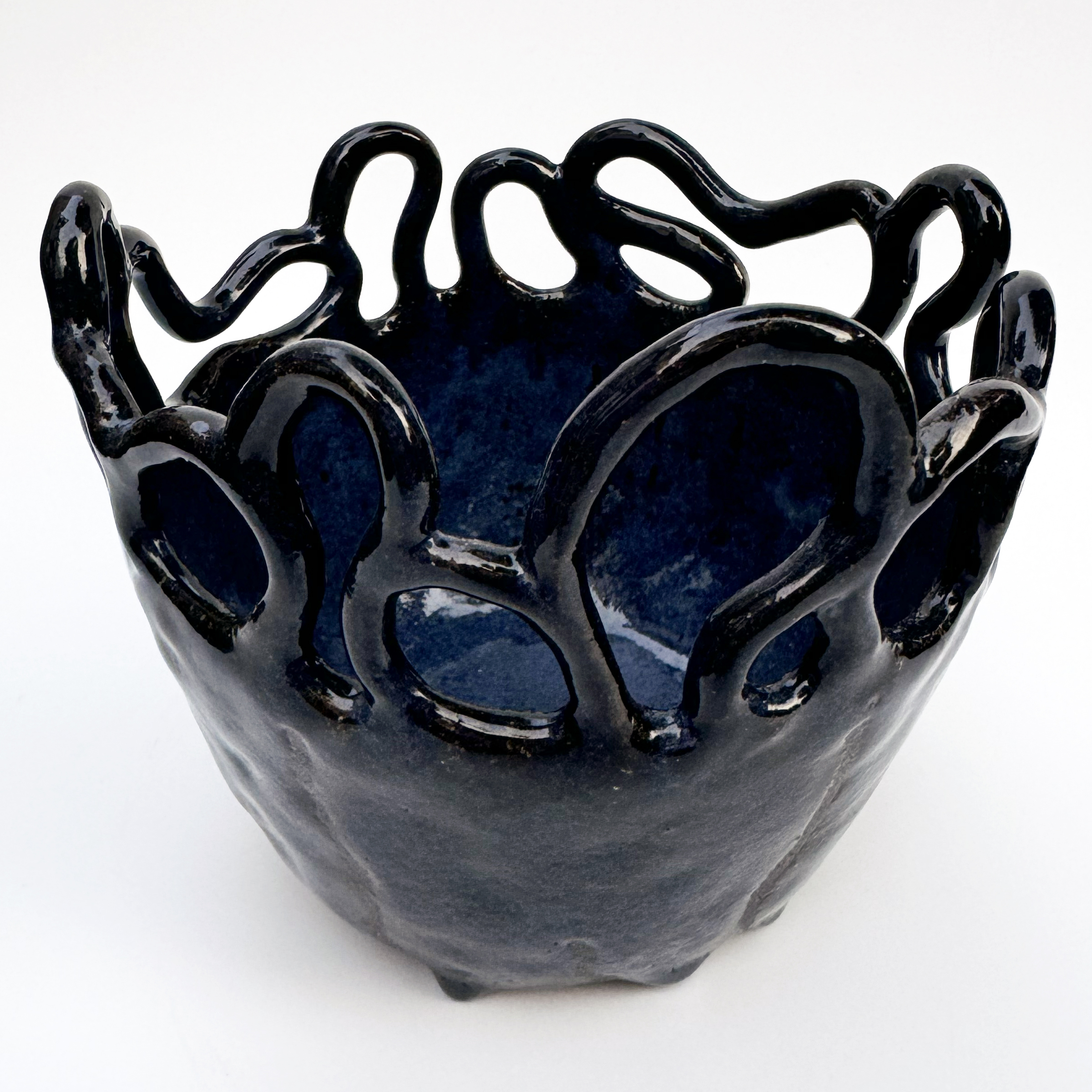 The black stoneware coils at the rim of the bowl can be used as handles, and they are arranged in a random pattern.