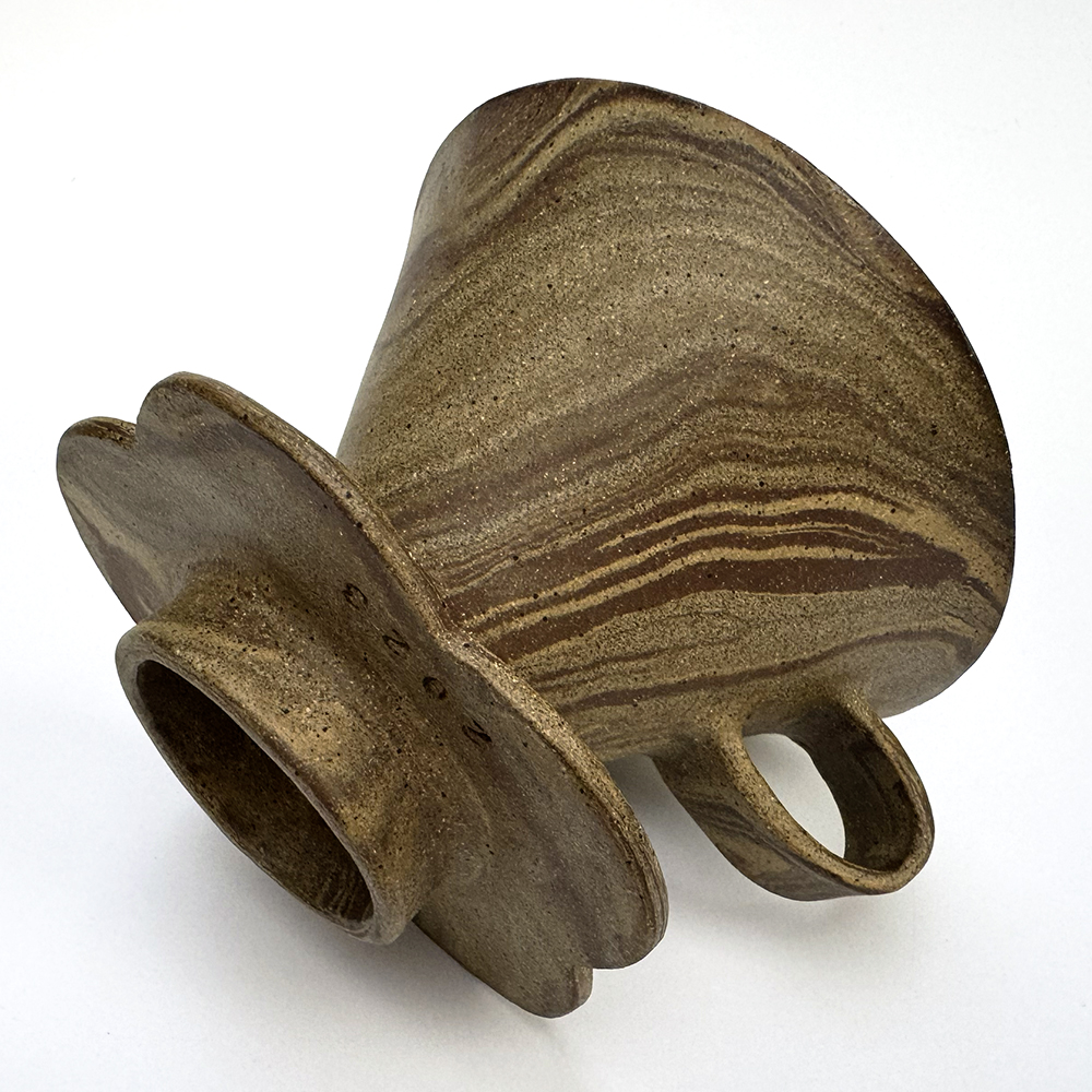 A handled V60-style coffee cone is mdae of multiple clay bodies that have been marbled together to create a striated design.