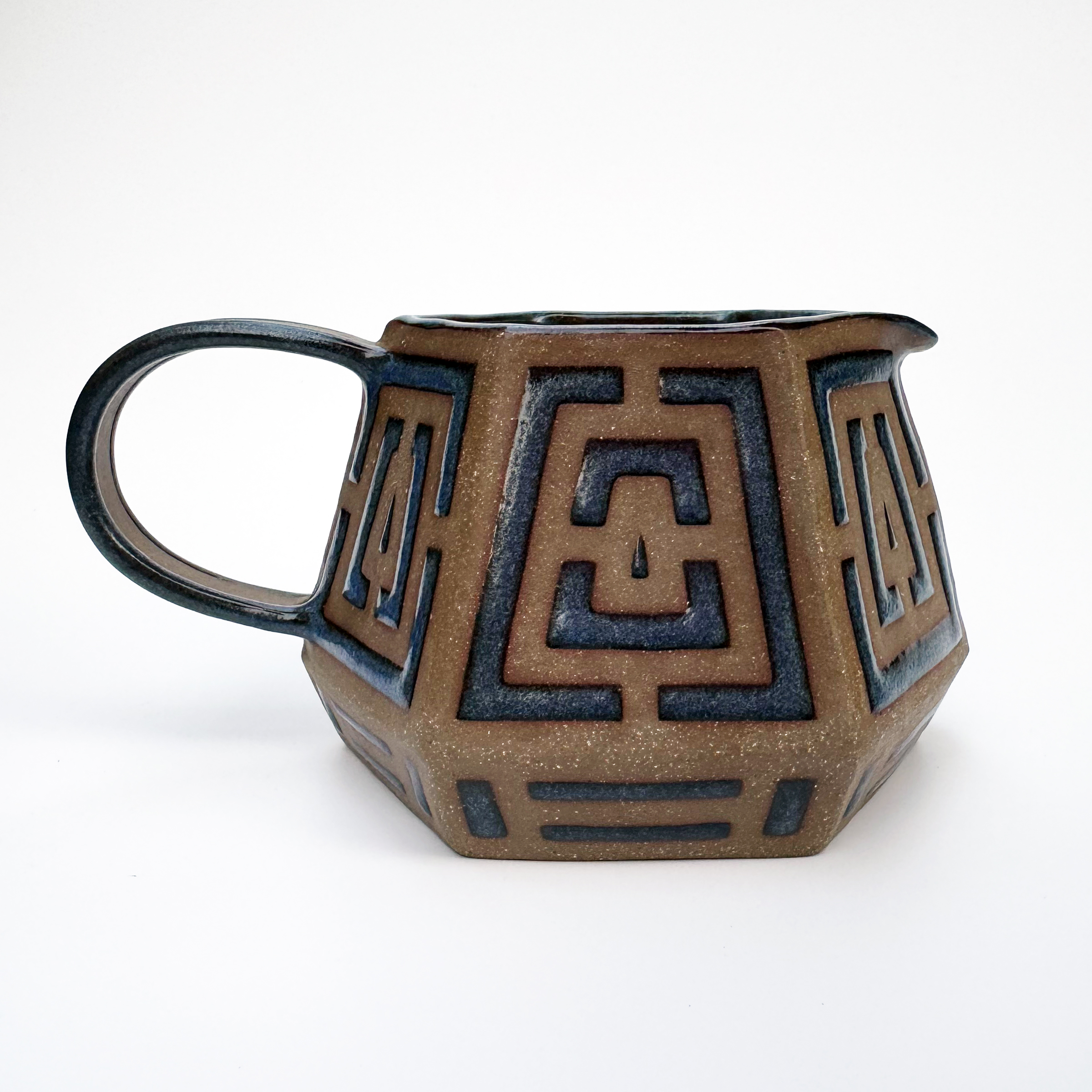 This medium brown stoneware pitcher has a squat, geometric form with a hexagonal base and opening.