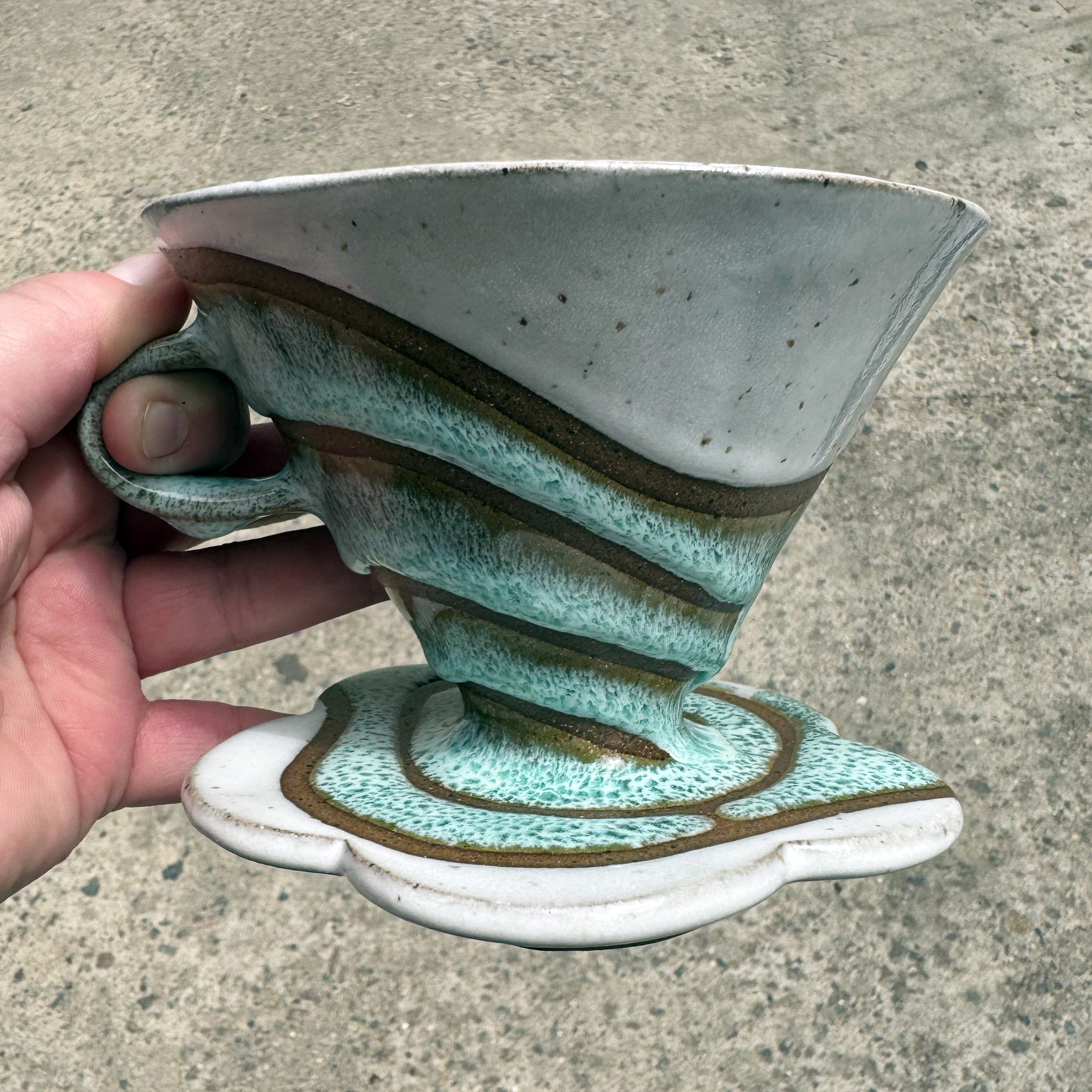 This ceramic v60 coffee cone has a glossy white top and bottom. Speckles show through the white glaze.