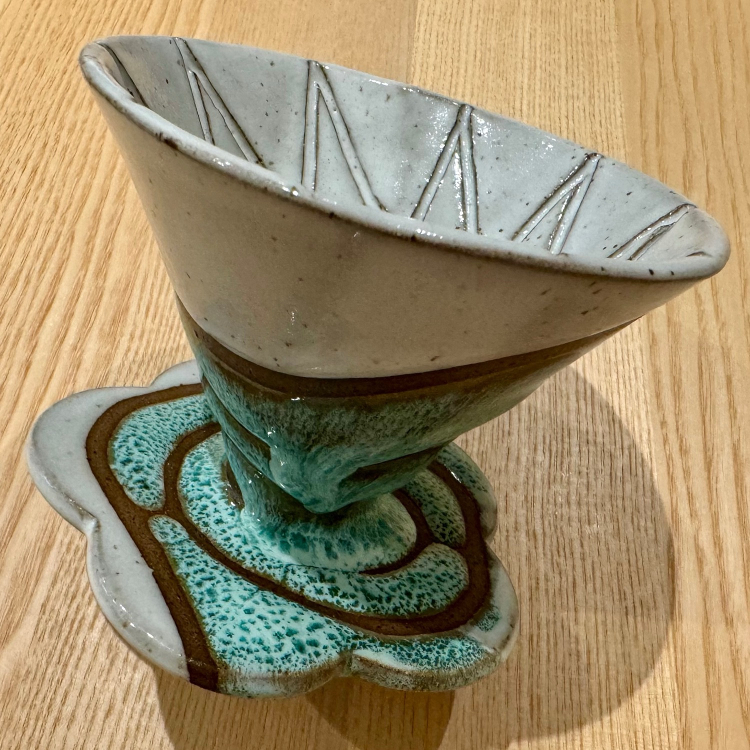 This glaze design is part of a v60-style coffee cone: the white and sea foam colored design inspired by climate change is on the outside, and the inside is glazed a glossy white.