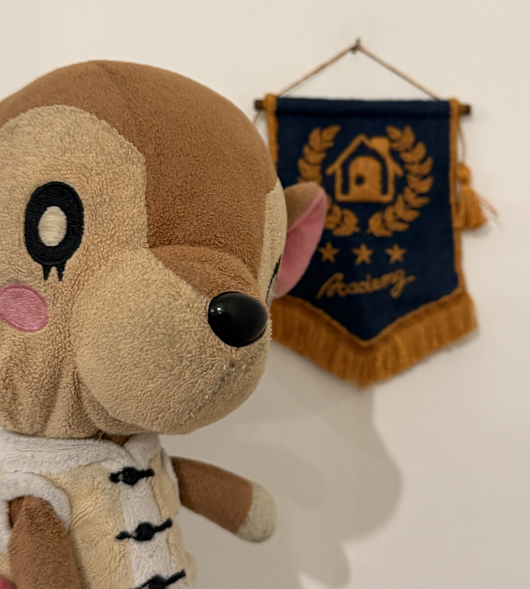 A small Fauna character plush near the Happy Home Academy mini-pennant that hangs on the wall.