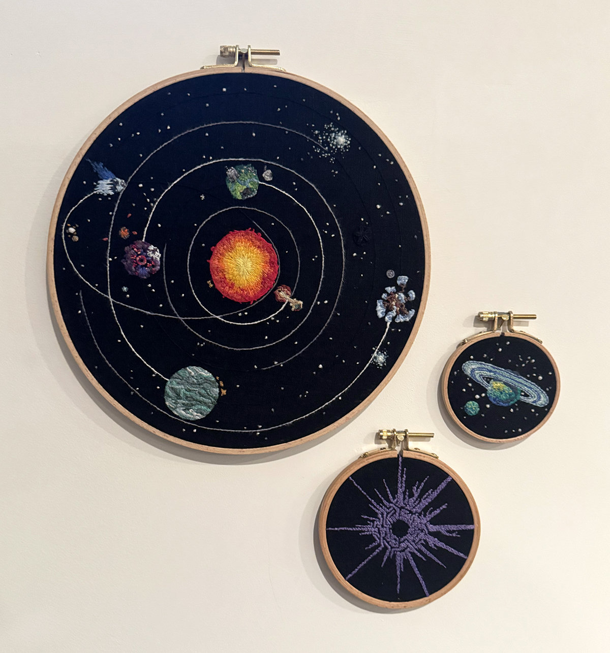 The 10-inch hoop with the main story's primary galaxy is positioned in the upper left, the 4-inch hoop with the symbol of the Eye of the Universe is to its bottom right, and the 3-inch hoop with the Owlk's home moon and the planet it orbits lies to the right of the main story's galaxy and is to the upper right of the Eye hoop. The part of the Eye symbol stitched in the style of the Owlk are the sections closest to the hoop containing the Owlk's home.