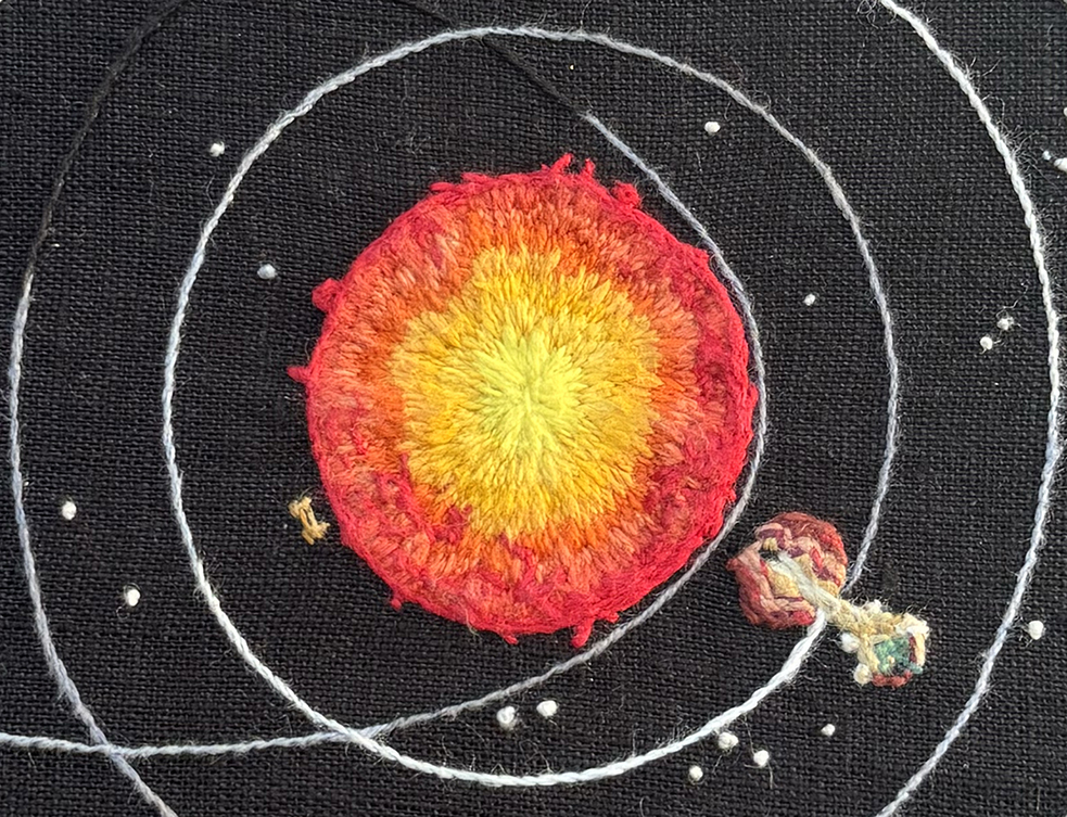 The center of the Outer Wilds solar system embroidery on a black linen background: the Sun is embroidered in a gradient of colors from a bright yellow to oranges to reds with bright red scars and coronal loops at the edges. The gradient is in long and shorts, and the scars, outline, and coronal loops are in stem stitch in varying directions. A small Sun Station circles the Sun at roughly the 8 o'clock position on a clock in subtle gold hues. Orbital paths for the Hourglass Twins and Timber Hearth can be seen in a gradient from white to black following the planets. Timber Hearth itself is out of view here, and part of the Interloper's orbit can be seen. The Hourglass Twins are orbiting the Sun at about the 4 o'clock position. Burnt reds and browns make up the canyons of the Ember Twin with dense, small stitches. Light tan stitches flow between the two Twins representing the sand, and part of the Ash Twin's machinery is visible, also all done in small dense stitches in various tans. Small French knots in whites and greys of varying thread thicknesses make up the starfield in the background.