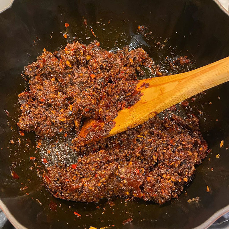 Photo of mapo tofu in progress: mushrooms fried in oil mixed with doubanjiang, douchi, ginger, garlic, and chili flakes make a paste.