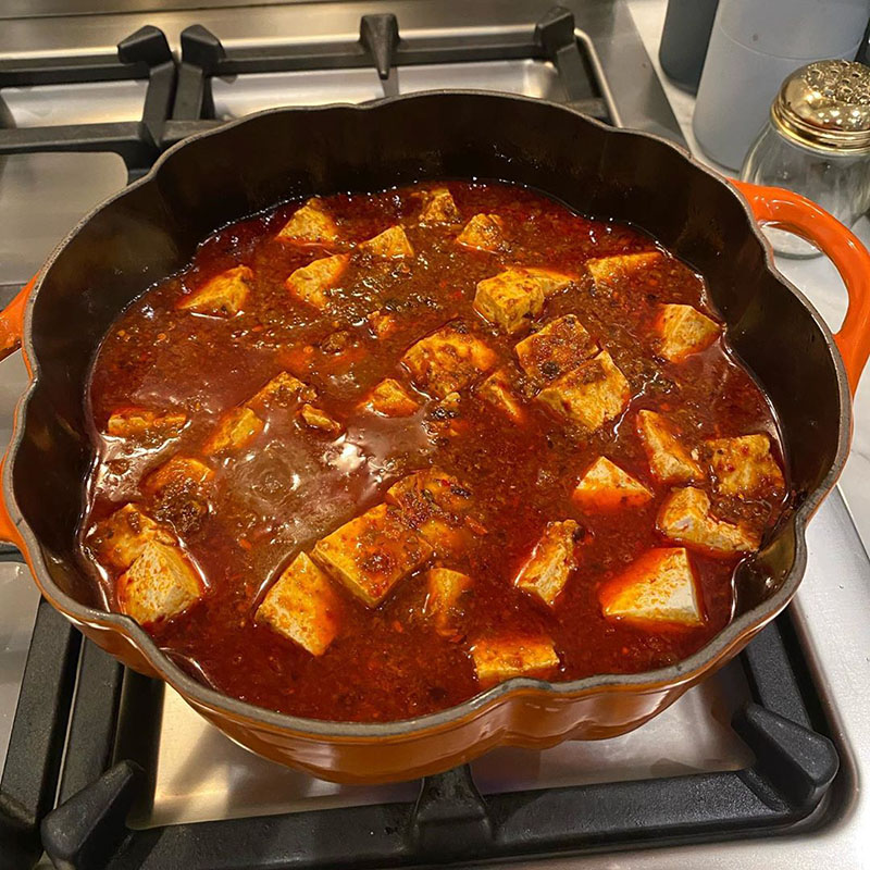 Photo of mapo tofu in progress: tofu has been nestled into the broth.