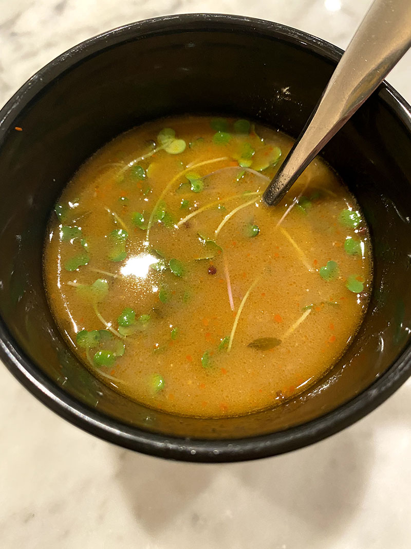 Close-up photo of a mug of pinto bean broth miso soup with sprouts