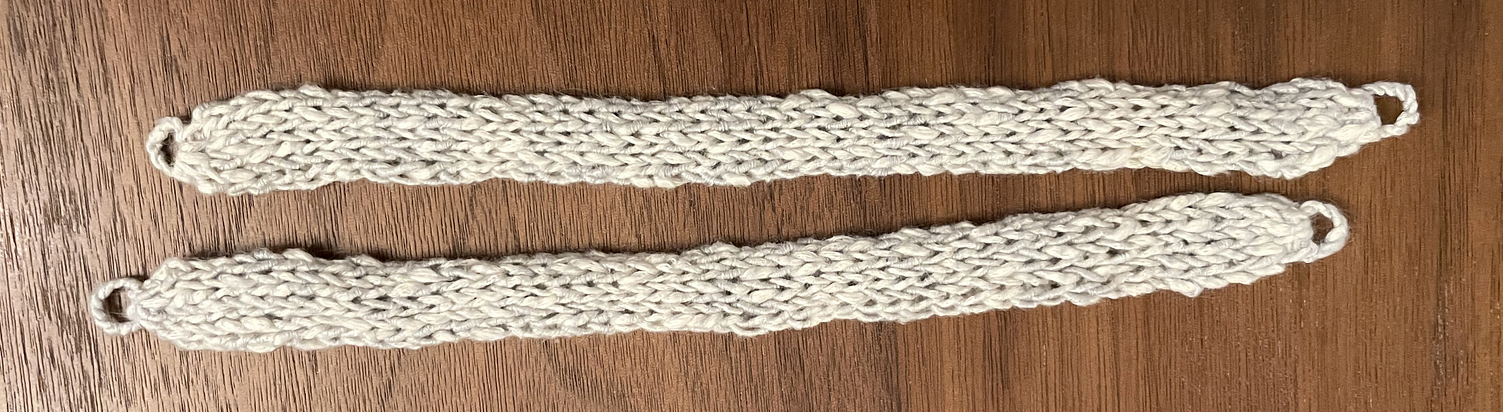 Two curtain ties lie flat on the table - each is finished with a small loop at both ends.