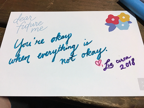 A postcard with scripted writing: Dear future me, You're okay when everything is not okay. ♡, Liz circa 2018